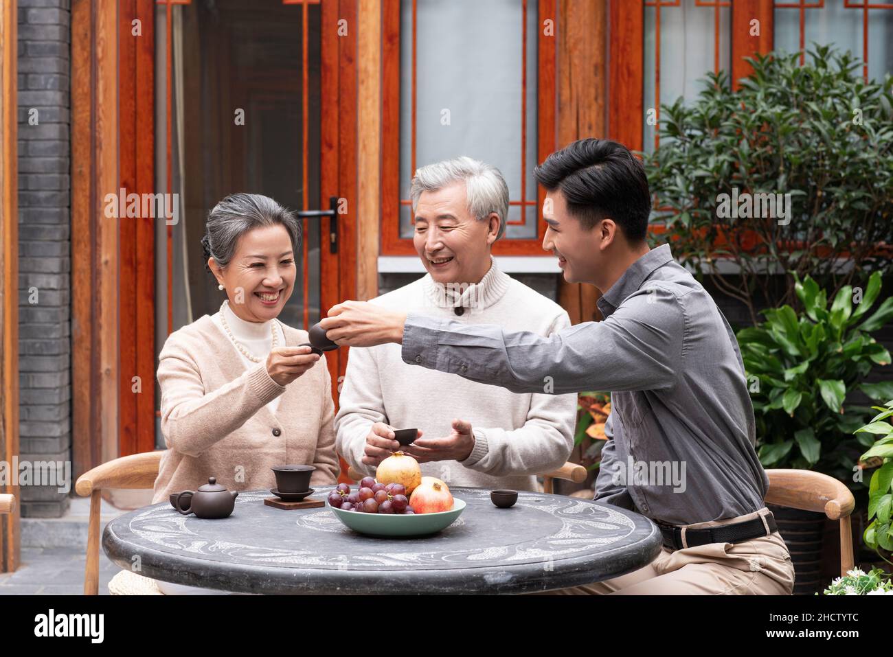 Famiglie felici che bevono il tè e chiacchierano nel cortile Foto Stock