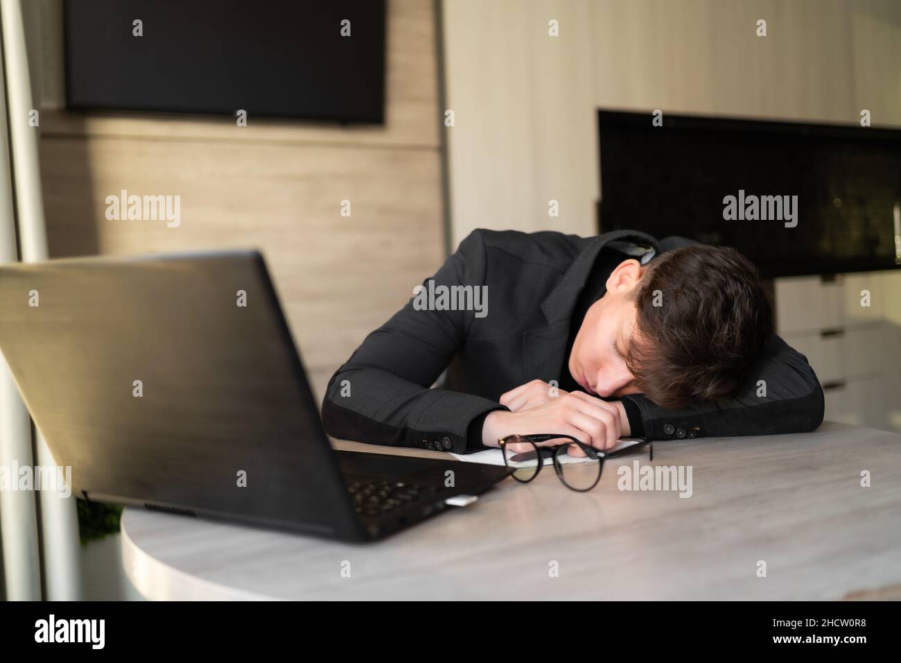 Lavoratore di sonno sul posto di lavoro, dipendente stanco che si trova sul tavolo, uomo d'affari che dorme in ufficio, lavoro di routine, mancanza cronica di sonno, insonnia Foto Stock