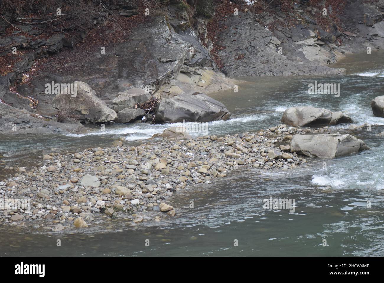 Primo piano di un fiume schiumoso e che scorre lungo le rocce in inverno Foto Stock
