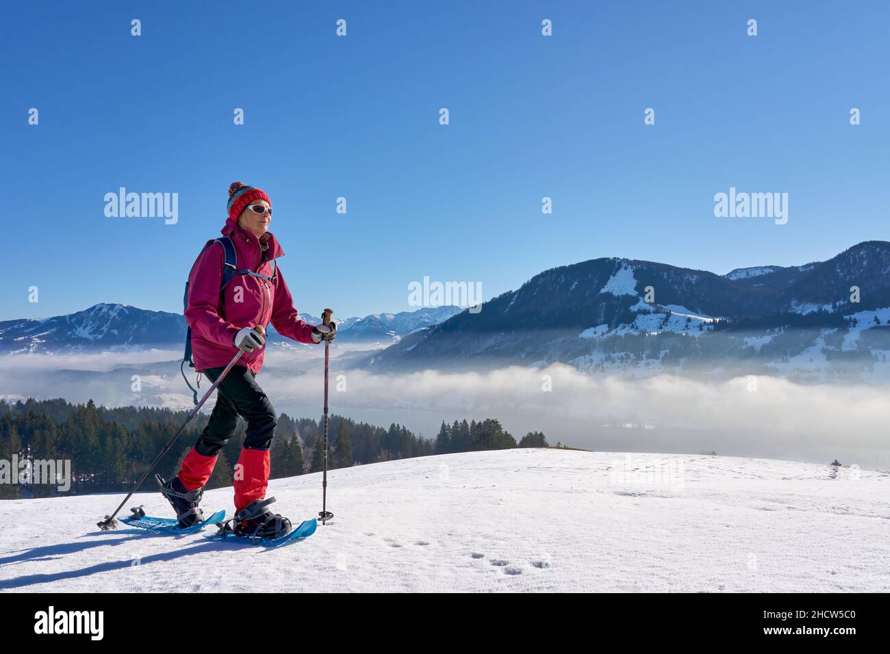 Donna anziana, molto attiva e simpatica, con racchette da neve nelle alpi di Allgau, sopra il lago Alpsee e Immenstadt, Baviera, Germania Foto Stock