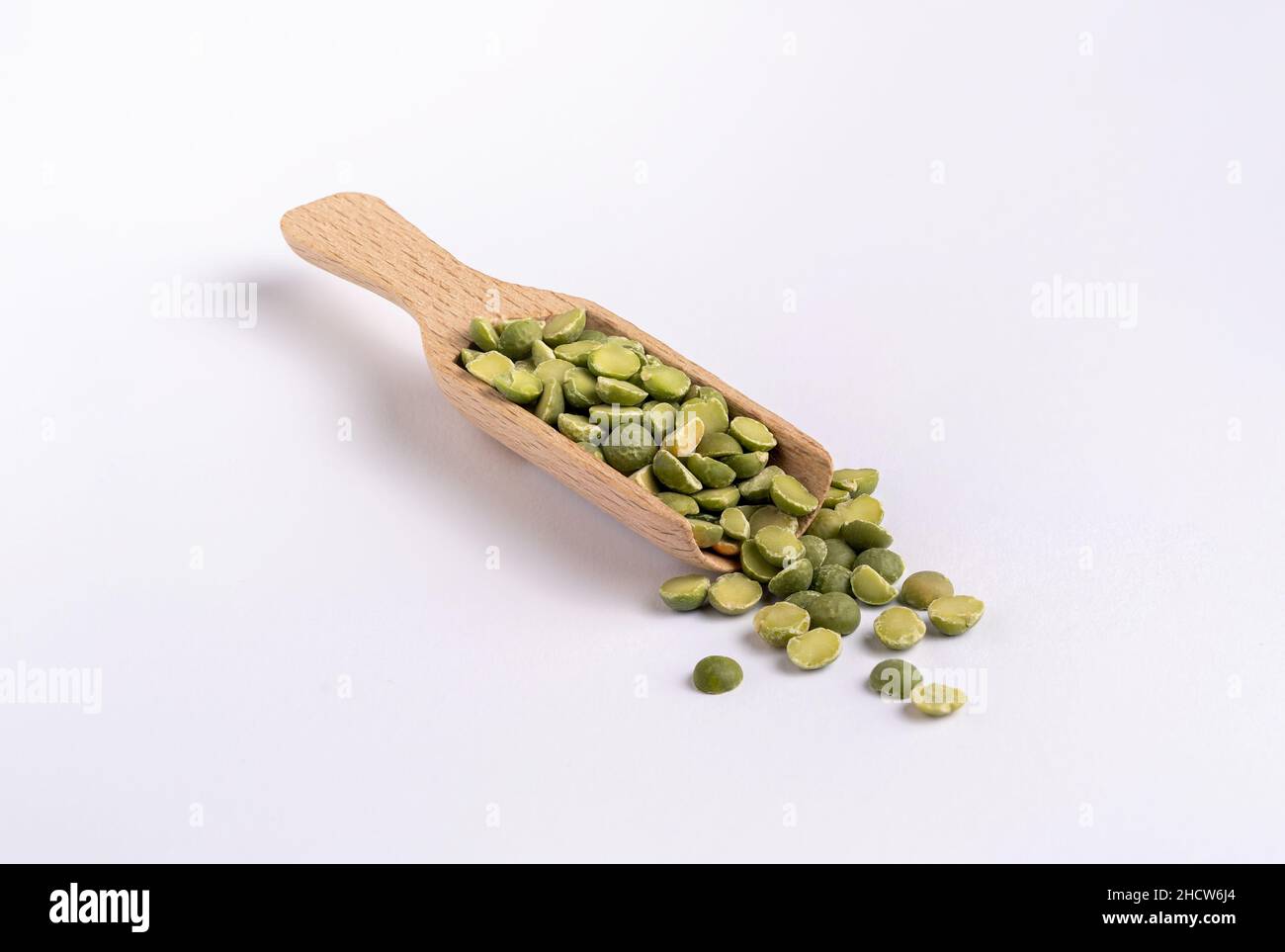 Piselli spaccati verdi in un misurino di legno su sfondo bianco (usati per la zuppa olandese di piselli) Foto Stock