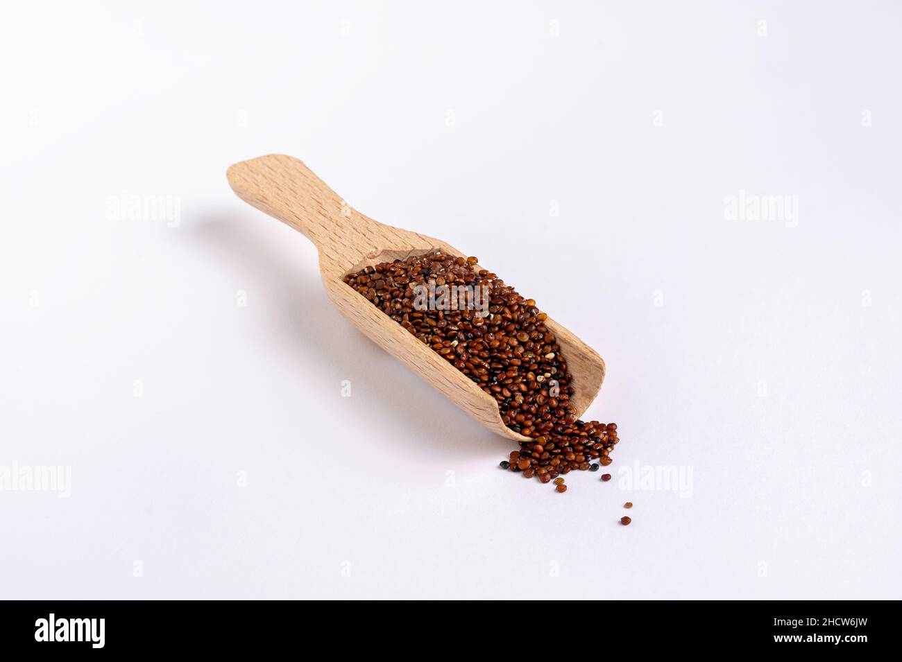 Quinoa rossa in un misurino di legno su sfondo bianco, spazio copia Foto Stock