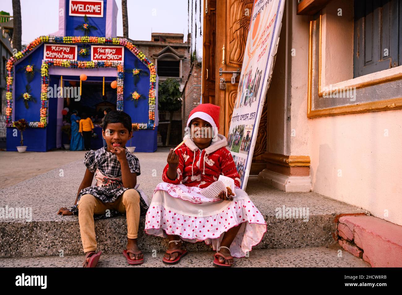 I bambini provenienti da villaggi distanti diversi celebrano il Santo Natale in una piccola chiesa e giocano di fronte a una grande foto di Gesù Cristo in Haulia, Bengala Occidentale, India. Foto Stock