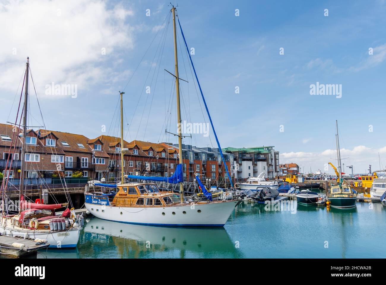 Barche a vela ormeggiate da appartamenti sul mare a Camber Quay nel porto di Portsmouth, Hampshire, costa sud Inghilterra Foto Stock