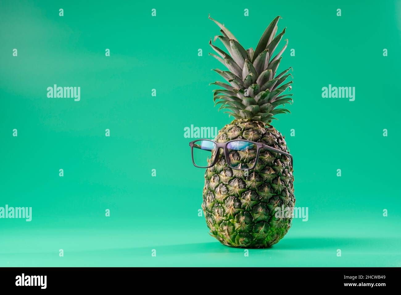 Interpretazione della frutta di ananas in un'immagine umana come in medicina oftalmica con vetri su sfondo verde. Spazio di copia Foto Stock
