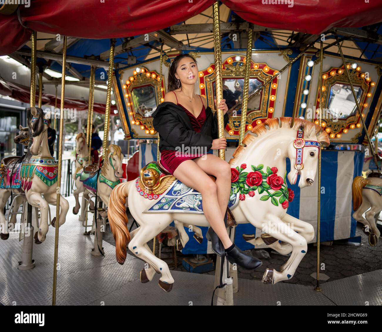 Giovane donna asiatica che cavia un merino di Natale Go Round Foto Stock