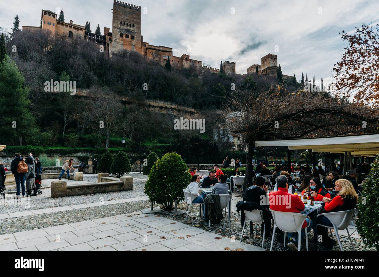 Granada, Spagna - 26 dicembre 2021: Persone che cenano fuori con la vista del Palazzo Alhambra a Granada, Spagna Foto Stock