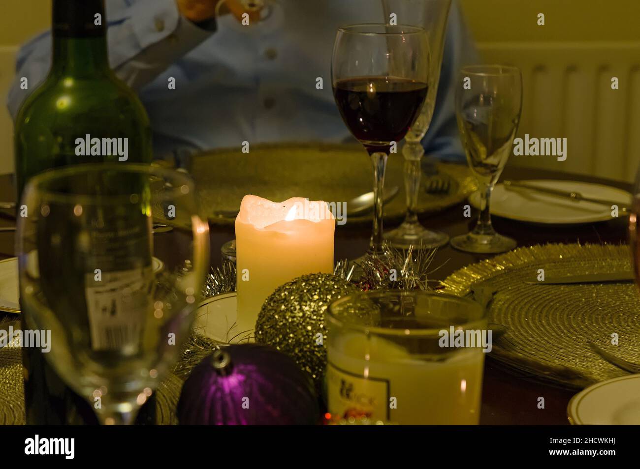 Tavolo a lume di candela prima o dopo una cena di Natale con bicchieri e piatti defocalizzati nella sala da pranzo Foto Stock