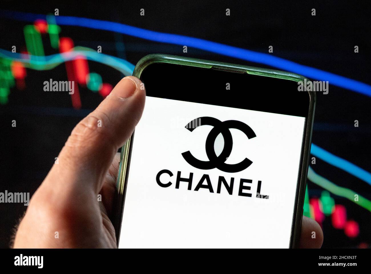 Cina. 4th Dic 2021. In questa illustrazione della foto il logo Chanel, marchio cosmetico francese multinazionale di bellezza, visto su uno smartphone con un grafico di indice di borsa economica sullo sfondo. (Credit Image: © Budrul Chukrut/SOPA Images via ZUMA Press Wire) Foto Stock