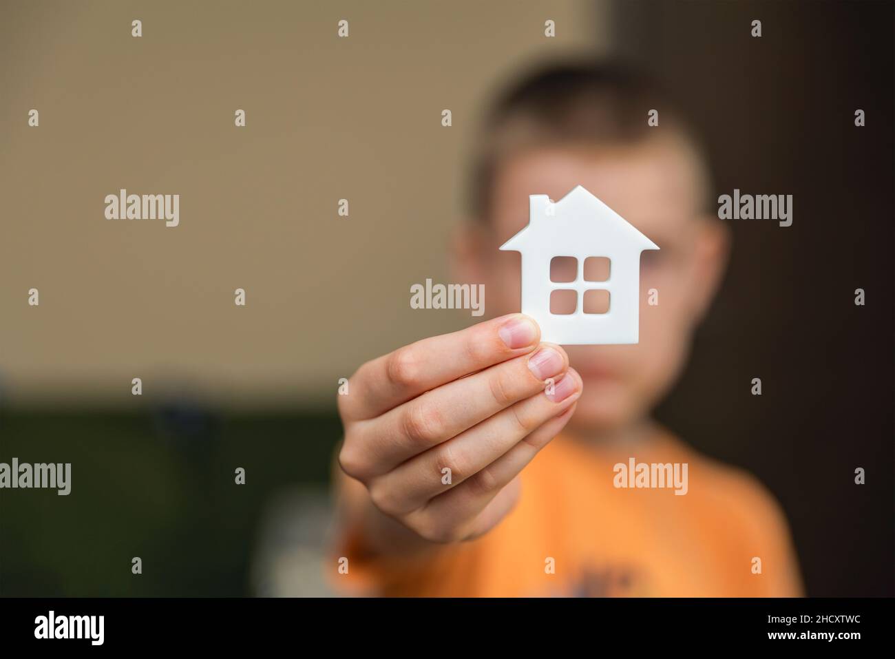 Orfanotrofio, bambini nell'orfanotrofio. Il bambino sta tenendo una piccola statuina a forma di casa, primo piano. Concetto di adozione. Luogo per il testo Foto Stock