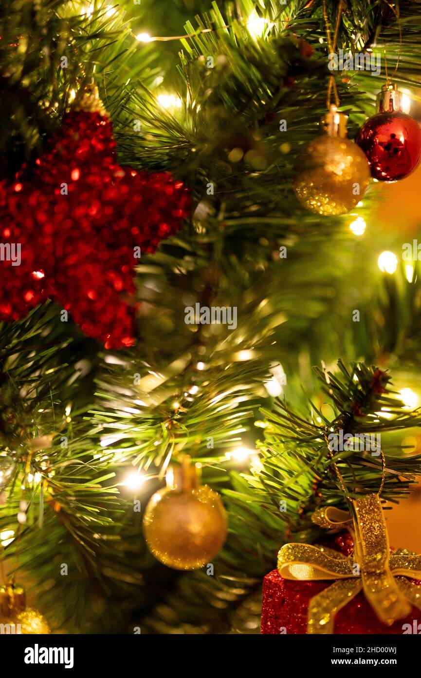 Scatto verticale di un ramo di albero di Natale con luci e ornamenti Foto Stock