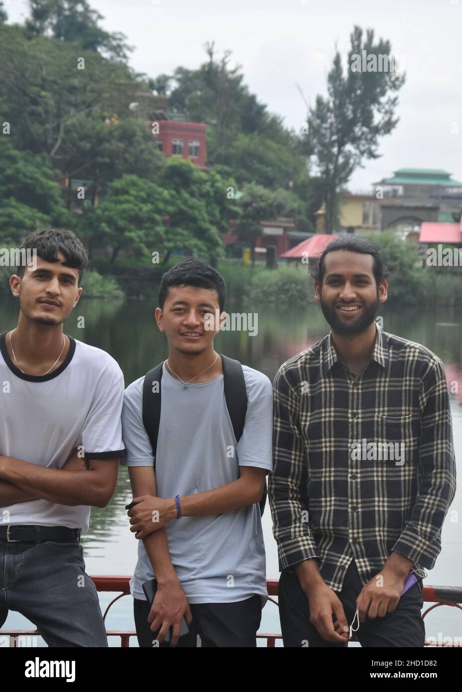 Vista frontale del sud asiatico tre amici maschi in posa per foto accanto al lago con guardare la macchina fotografica Foto Stock