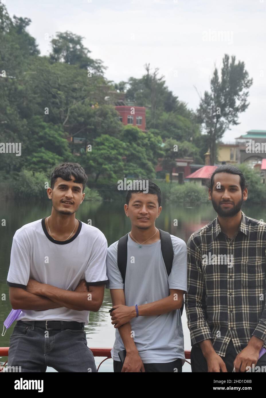 Vista frontale del sud asiatico tre amici maschi in posa per foto accanto al lago con guardare la macchina fotografica Foto Stock