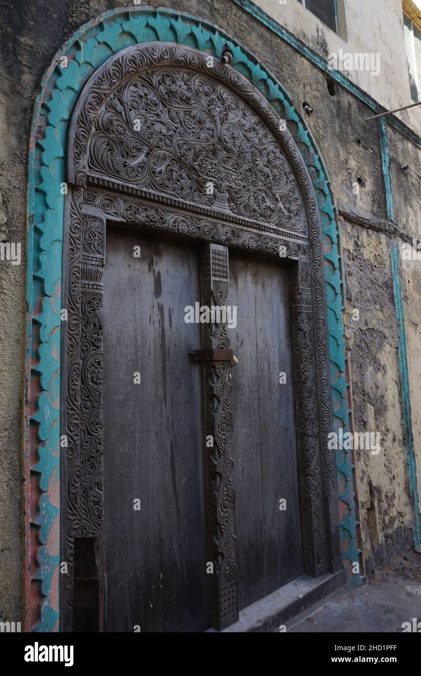 Primo piano su una porta in legno ornata con motivi tradizionali a Lamu, Kenya Foto Stock