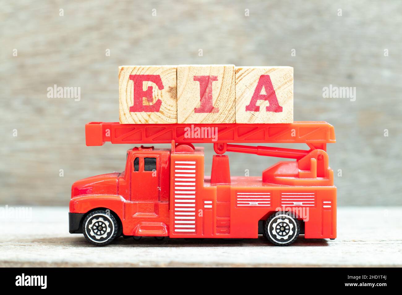 Il camion della scala del fuoco tiene il blocco della lettera in parola EIA (abbreviazione di valutazione di impatto ambientale) su sfondo del legno Foto Stock