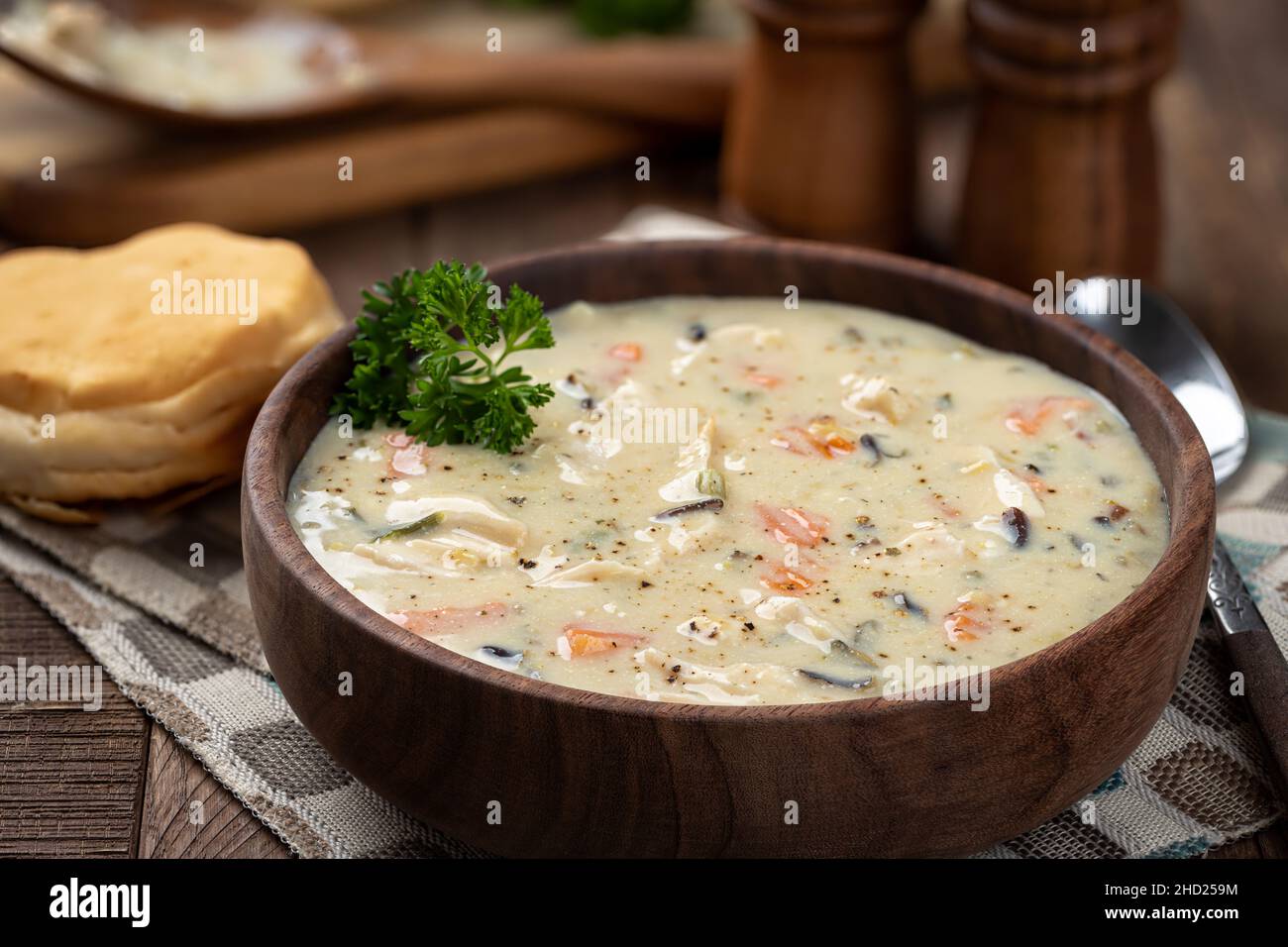 Primo piano di una ciotola di pollo cremoso e zuppa di riso guarnita con prezzemolo su un rustico tavolo di legno Foto Stock