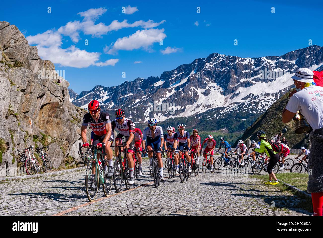 Un gran gruppo di ciclisti che corre sulla Tremola San Gottardo al Tour de Suisse 2021, circondando montagne innevate. Foto Stock