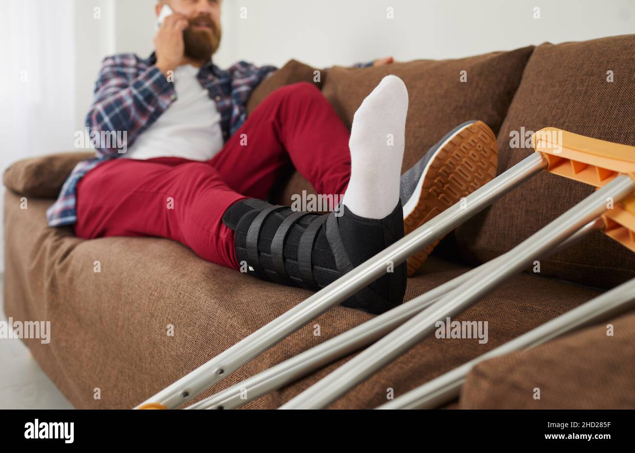 Uomo malato con trauma rilassarsi sul divano parlare al telefono Foto Stock