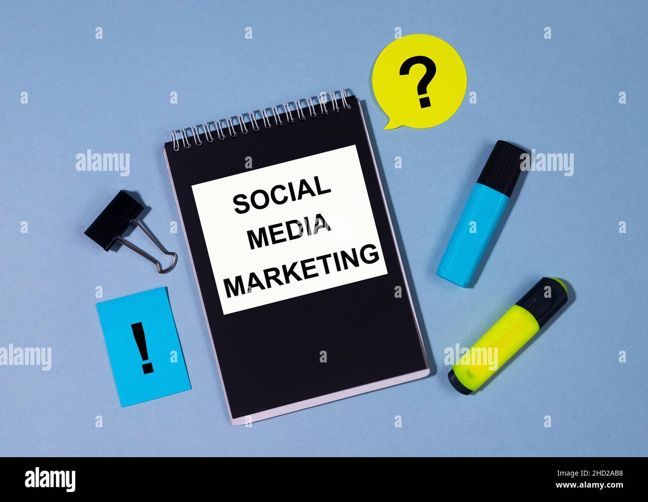 SMM Social Media Marketing scritto su blocco note con marcatori clip e memo nte intorno su tabella blu. Concetto SMM giallo blu e nero Foto Stock