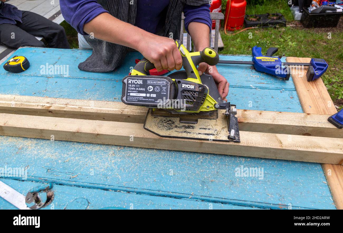 Persona che utilizza l'utensile elettrico Ryobi per segare il legno Foto Stock