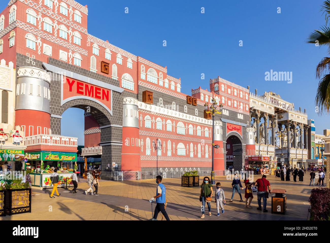 Dubai, Emirati Arabi Uniti, 10.01.21. Colorati edifici dei padiglioni dello Yemen e dell'Iran nel parco divertimenti Global Village di Dubai con gente che cammina. Foto Stock