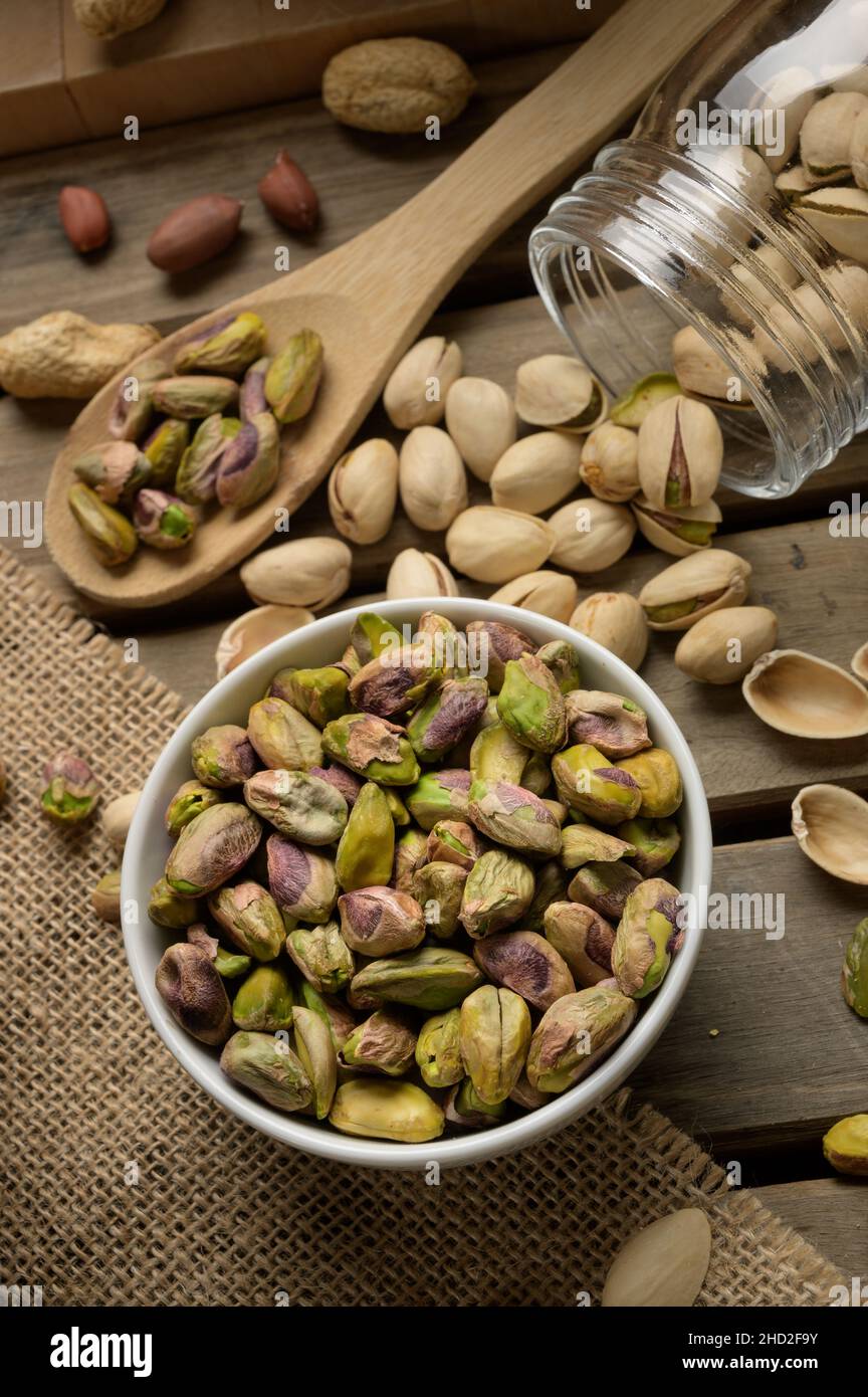 Ciotola e cucchiaio di legno con noci sane, pistacchi su sfondo di legno scuro Foto Stock