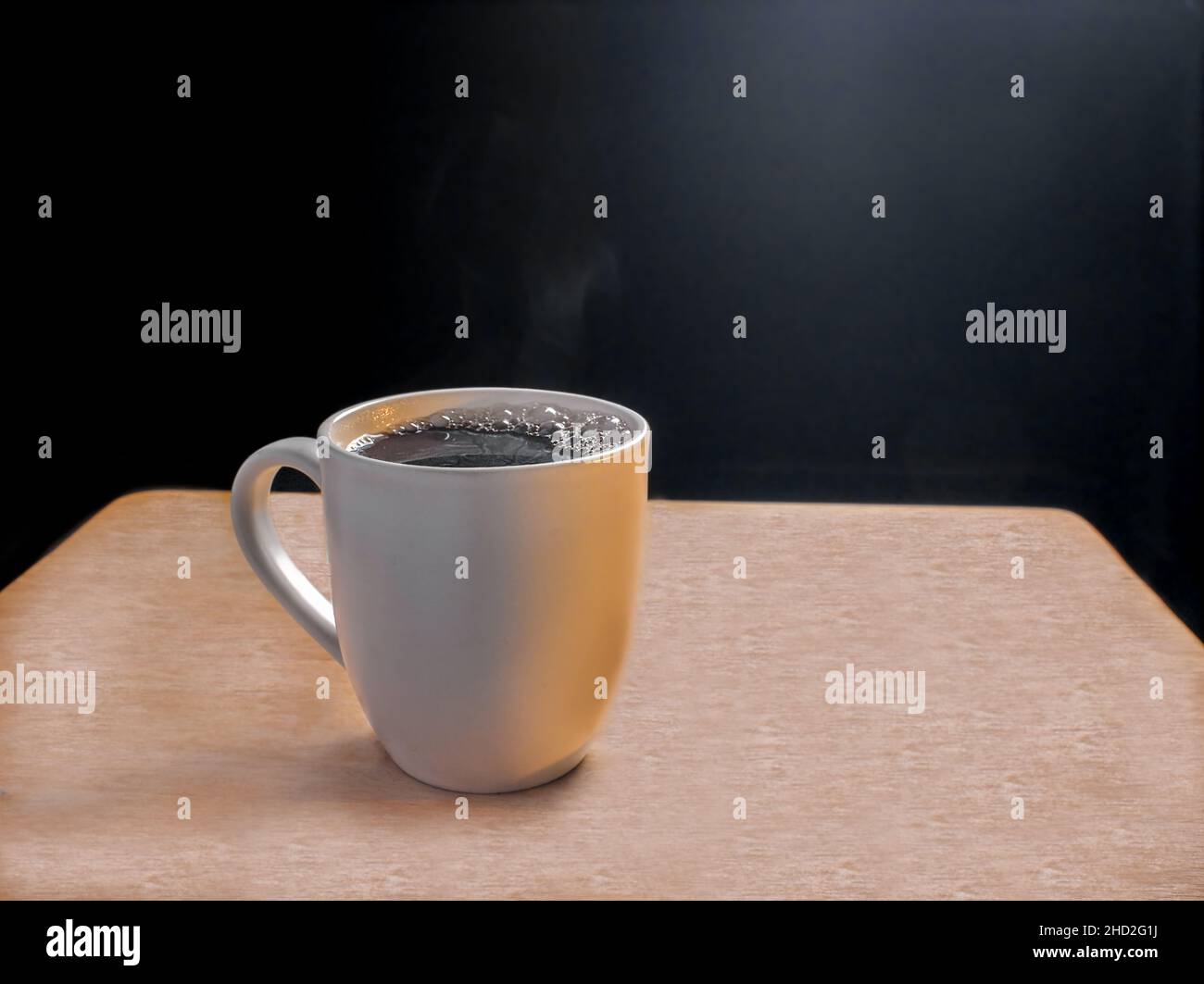 Fresh Brewed tazza di caffè nero su un tavolo di legno su uno sfondo nero con spazio copia. Foto Stock