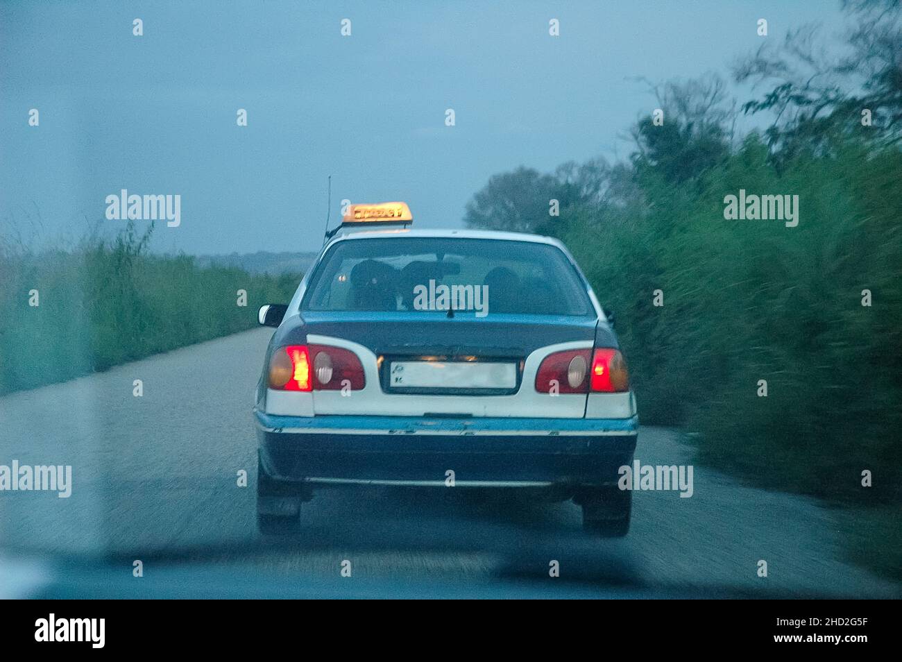 Vista posteriore di un taxi sulla strada in Congo al crepuscolo con palme. Ritorno a Pointe-Noire attraverso la vetrinetta. Foto Stock