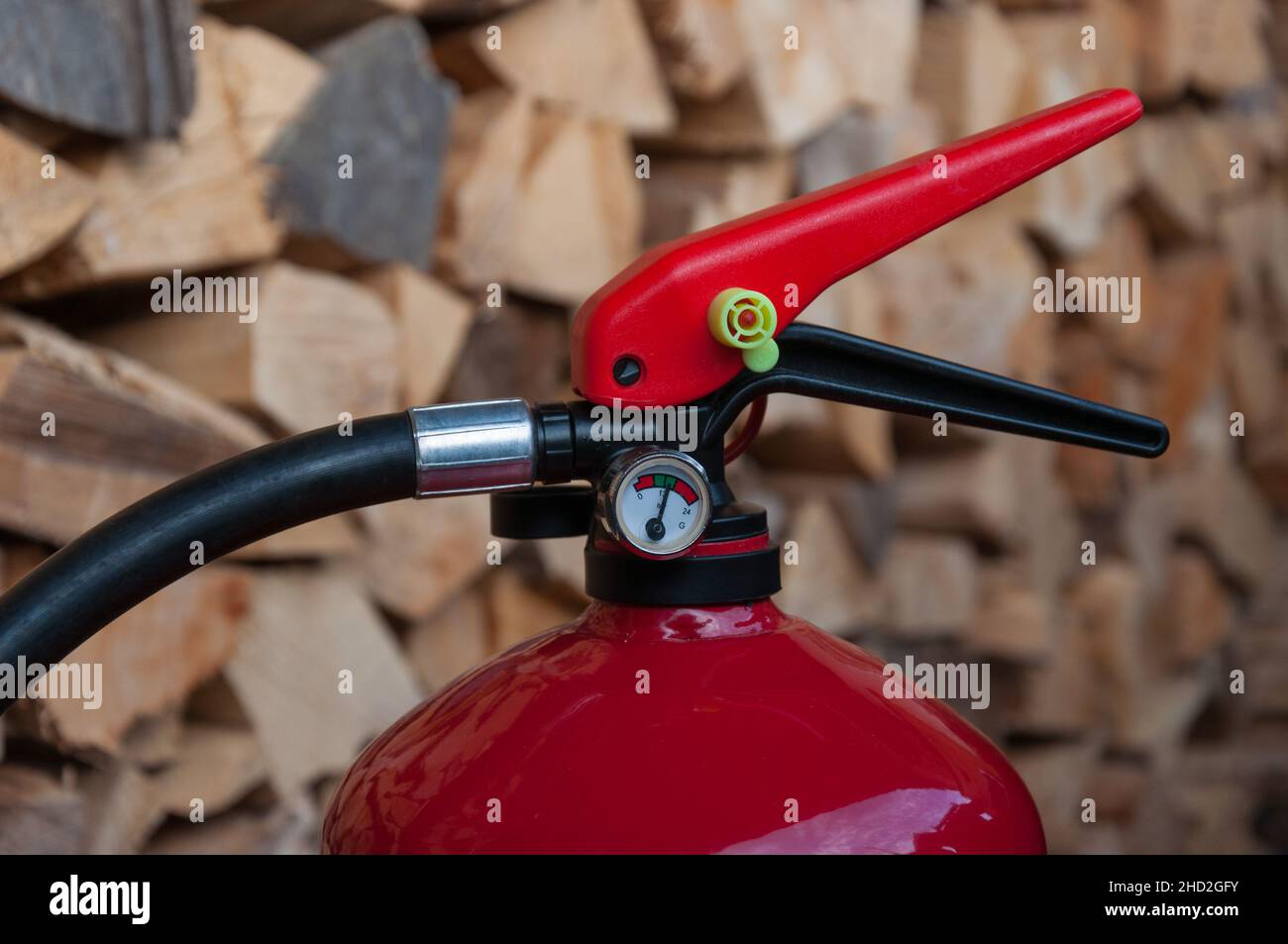estintore: dettaglio del manometro, cumulo di legno nel backgorund Foto Stock