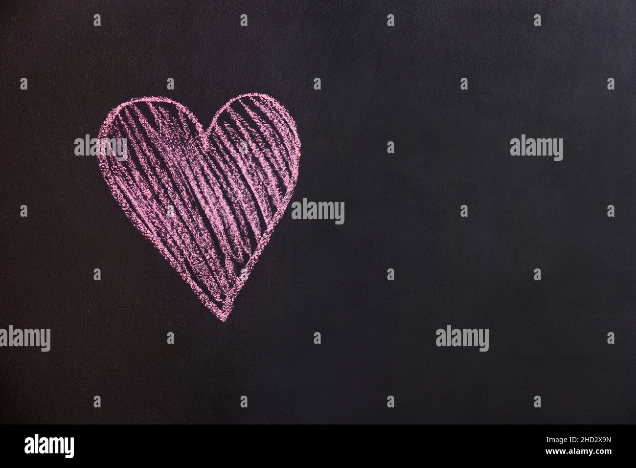 San Valentino simbolo. Cuore semplice disegnato in gesso rosa su una lavagna nera testurizzata. Spazio di copia sulla destra. Foto Stock