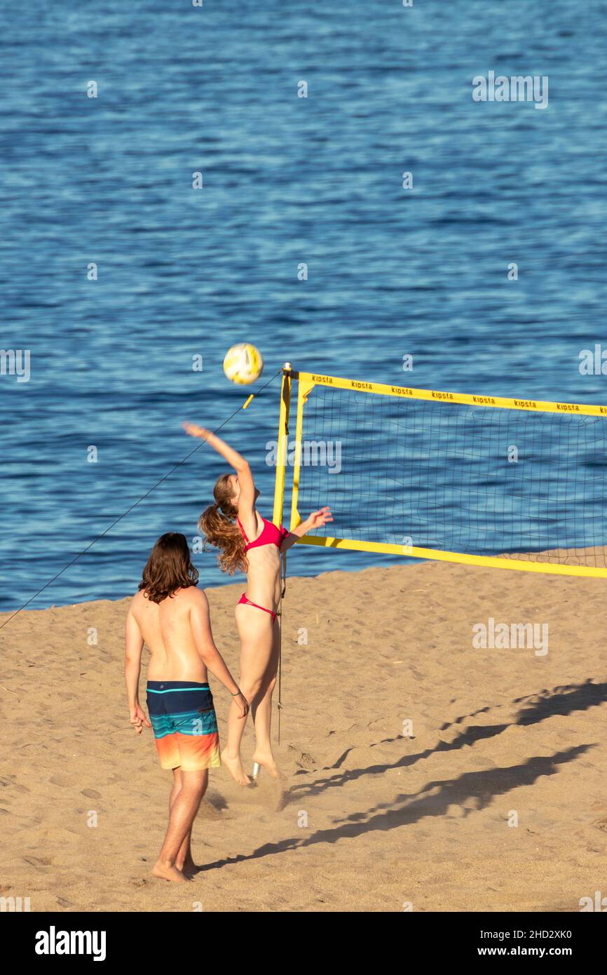 Coppia mista di un uomo e una donna che gioca a pallavolo sulla spiaggia sabbiosa di Pals in Spagna in una giornata di sole Foto Stock