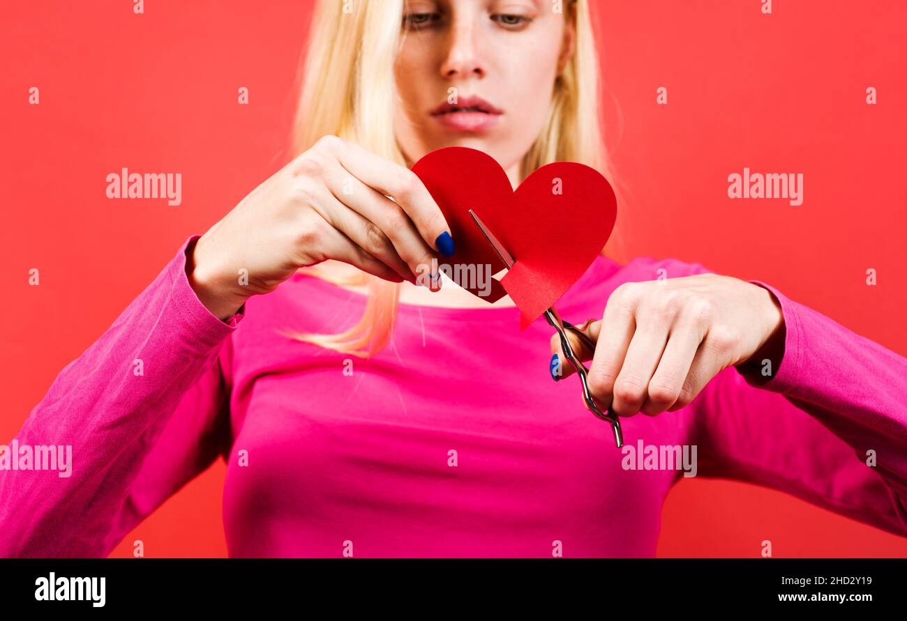 Ragazza con cuore rotto. Rottura dei rapporti. Donna triste taglio di carta a forma di cuore. Messa a fuoco selettiva Foto Stock