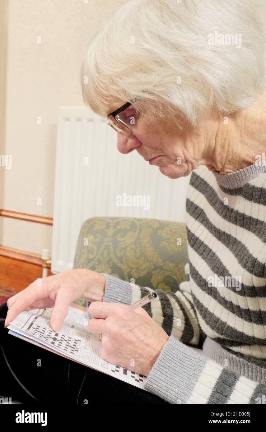 Anziana signora tenendo la mente attiva facendo il puzzle di cruciverba Foto Stock
