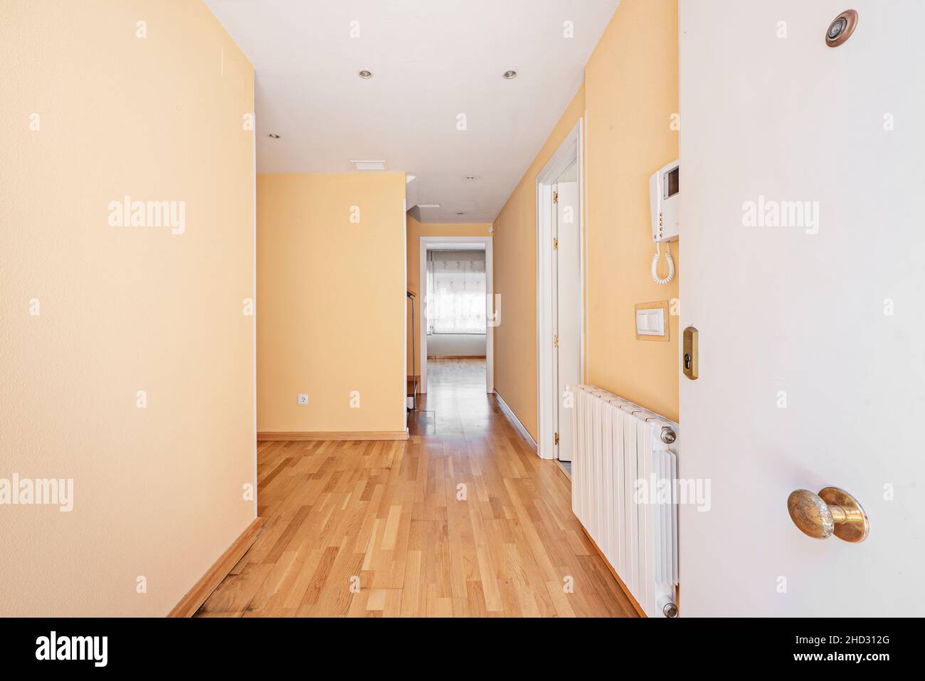Ingresso al piano terra di una casa indipendente con una porta bianca e un videocitofono sul radiatore in alluminio Foto Stock