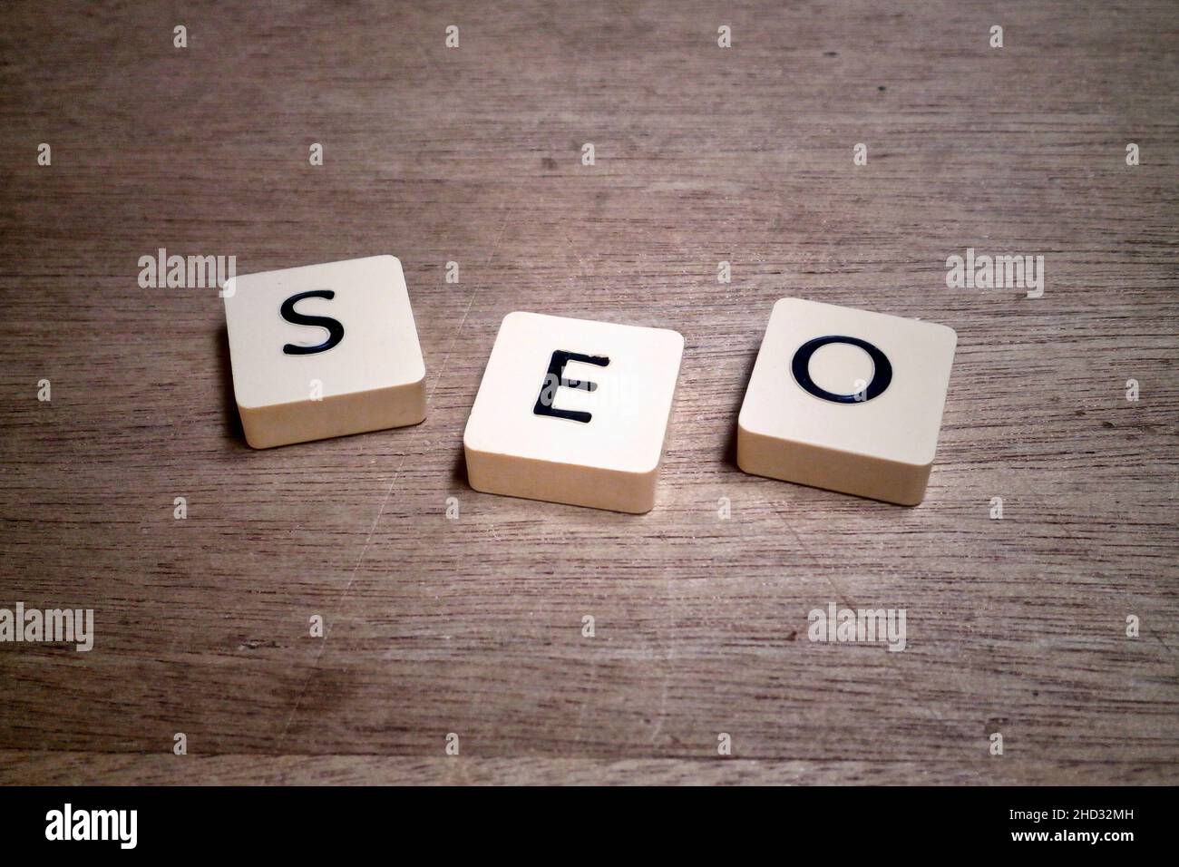 Piastrelle di plastica con lettere su un asse di legno che mostra l'acronimo SEO. Foto Stock