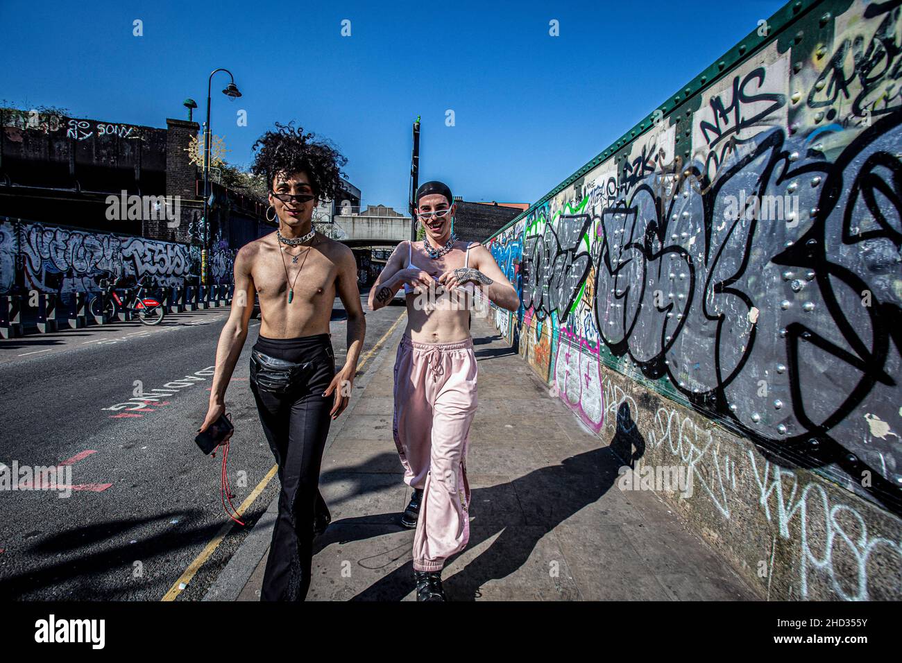 Coppia gay a piedi lungo Brick Lane Street a East London Foto Stock