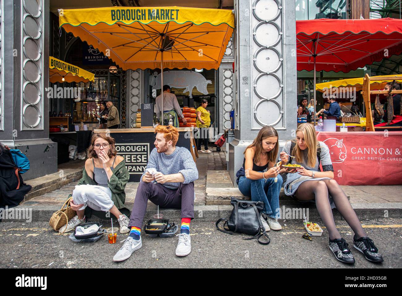 Le persone apprezzano il cibo di strada al Borough Market di Londra Foto Stock