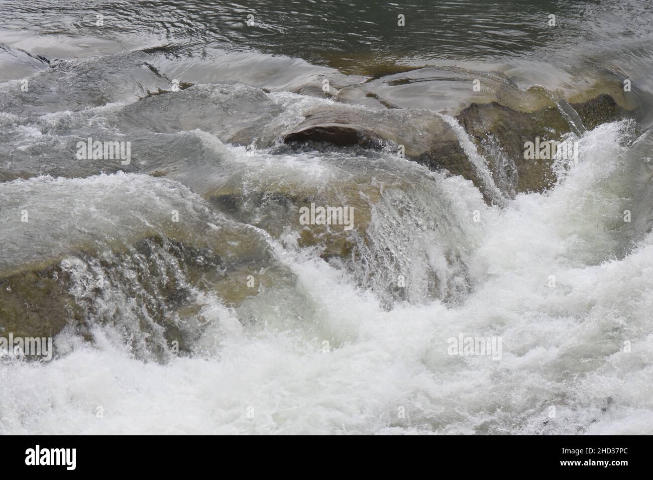 Primo piano di un fiume schiumoso e che scorre lungo le rocce in inverno Foto Stock