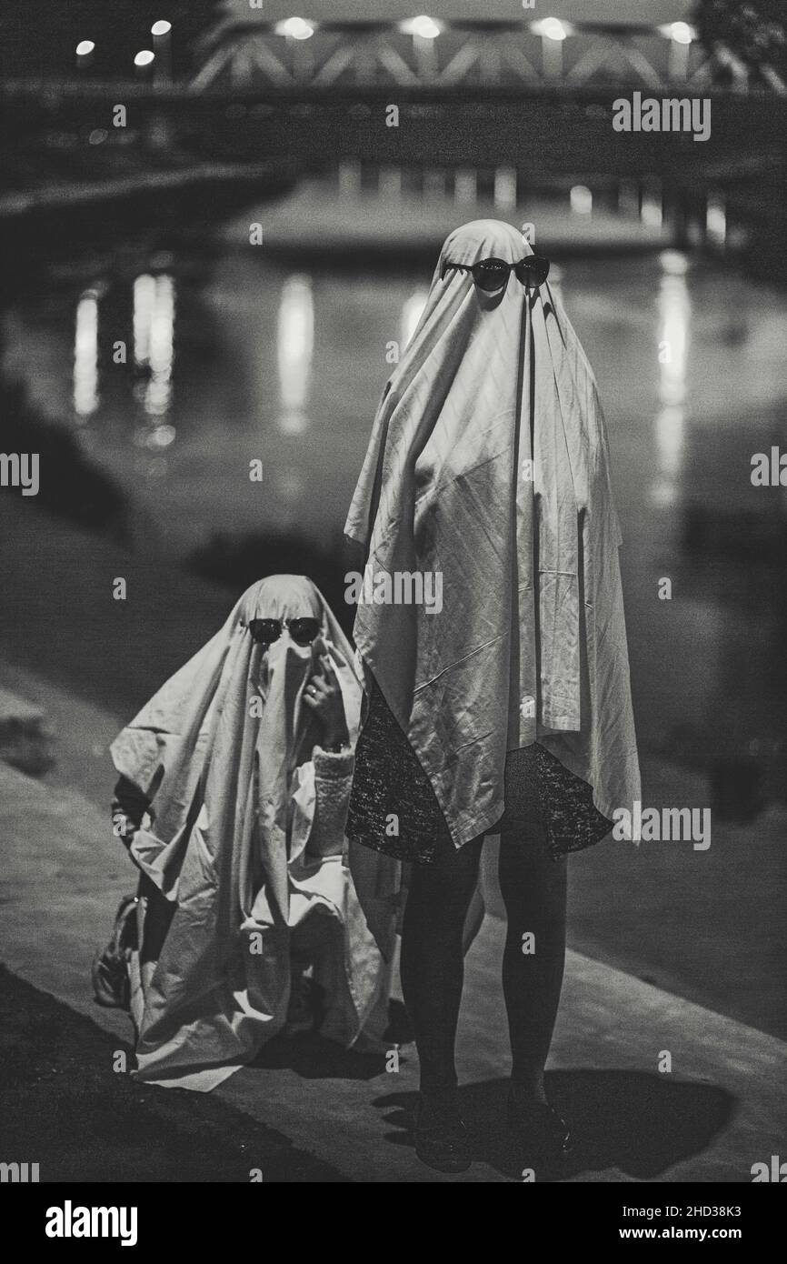 Foto verticale in scala di grigi di due persone vestite in un divertente costume fantasma Foto Stock