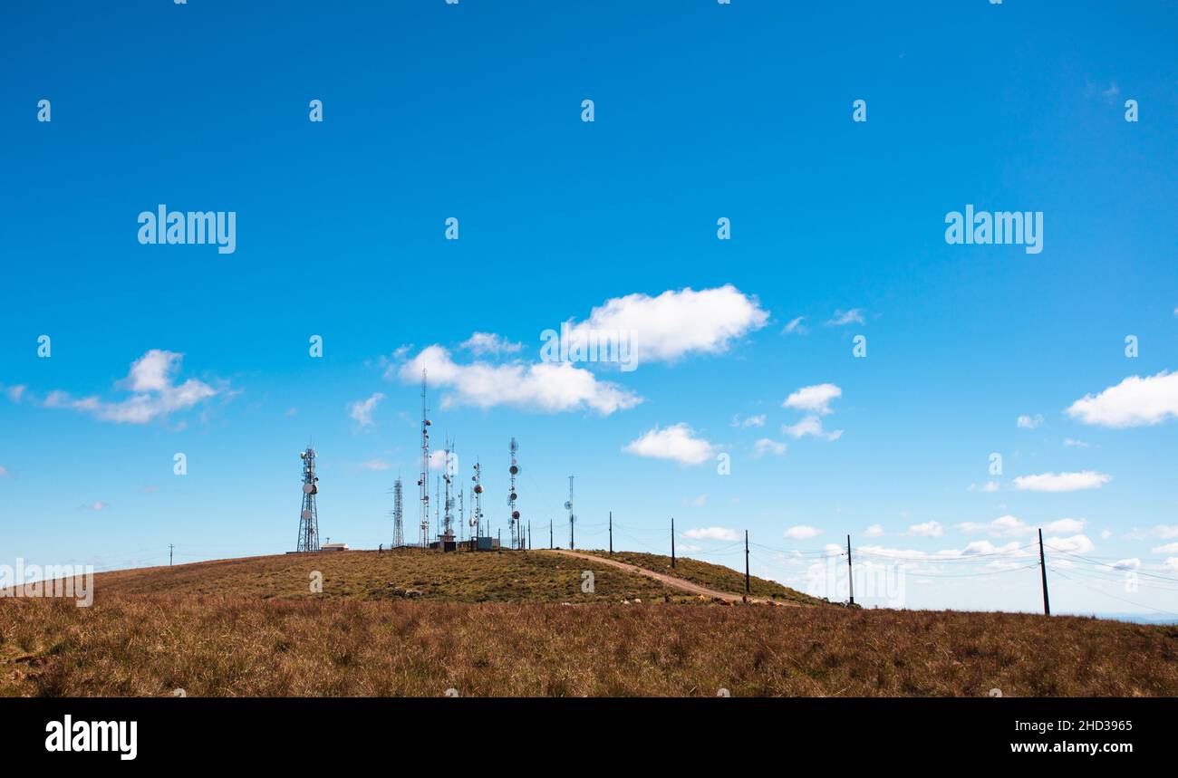 Cielo blu e collina con antenne per telecomunicazioni. Foto Stock