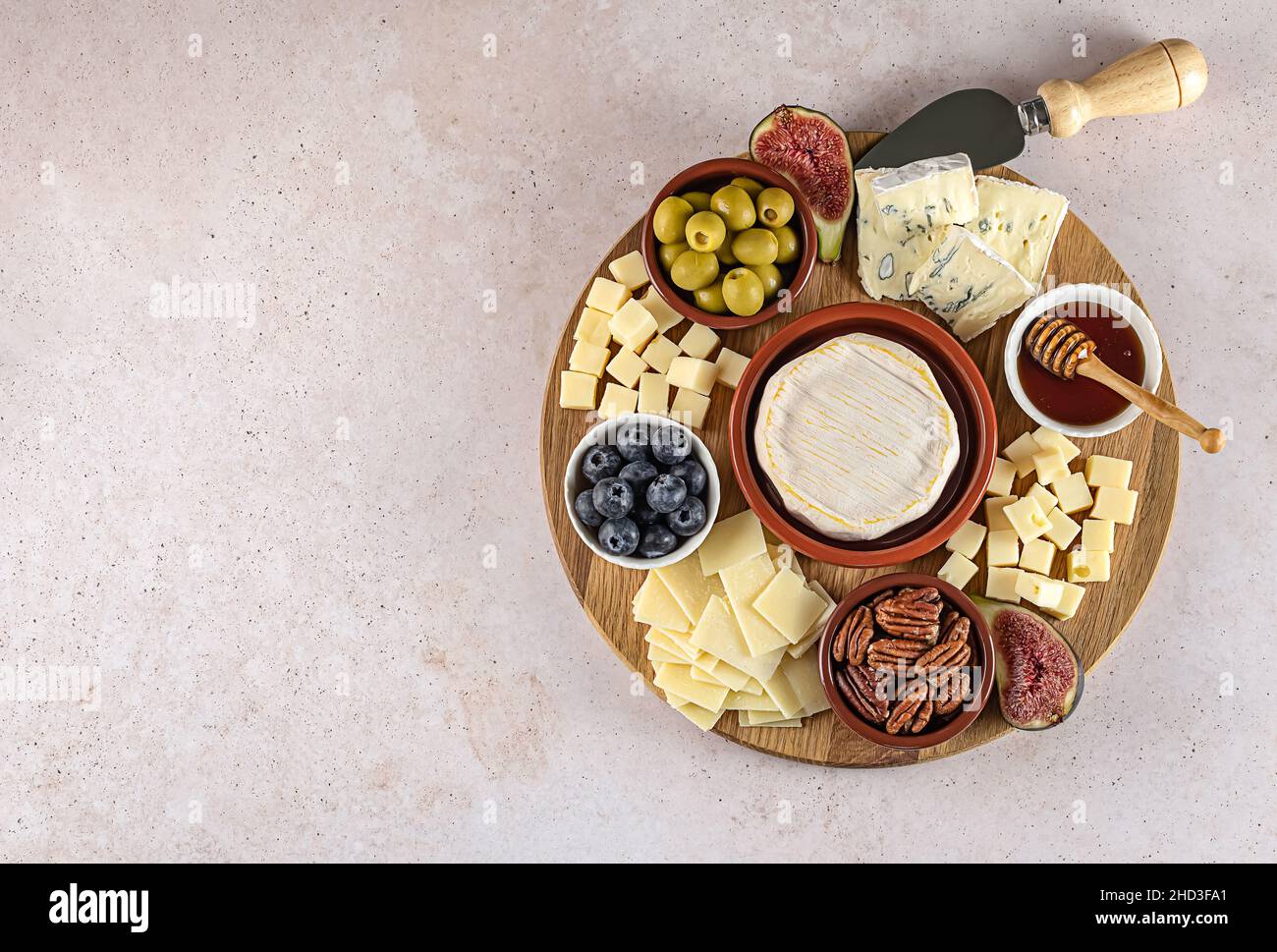 Vista dall'alto di gustosi formaggi a tavola con frutti di bosco, miele, noci, olive e formaggi Foto Stock