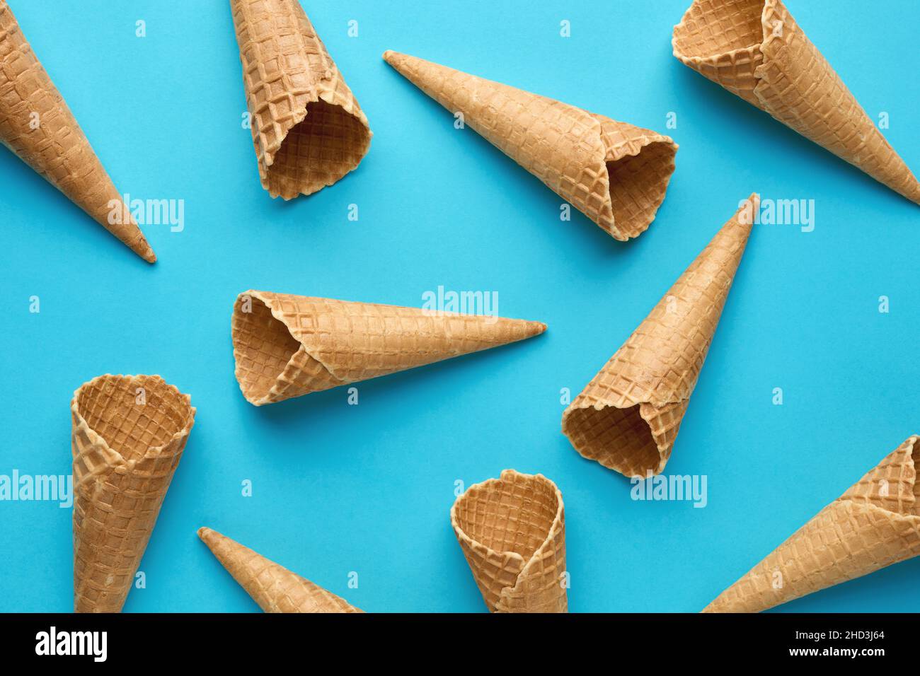 I coni di cialde per gelato vuoti si fondano su sfondo blu. Concetto di cibo estivo. Disposizione piatta. Foto Stock