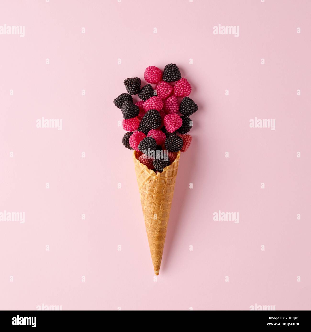 Cono gelato con lampone versato o bacche su sfondo rosa pastello. Concetto minimo di cibo per la vita morta creativa. Foto Stock