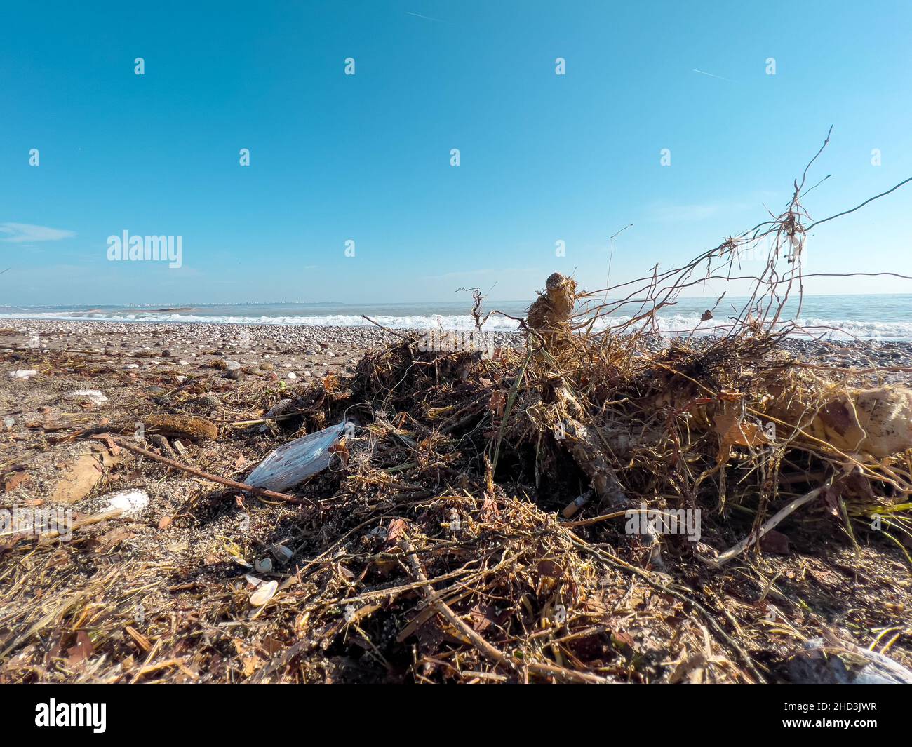 Si versano rifiuti sulla spiaggia della grande città. Svuotare le bottiglie di plastica sporche usate. Mare sporco spiaggia sabbiosa. Inquinamento ambientale. Problema ecologico. Foto Stock