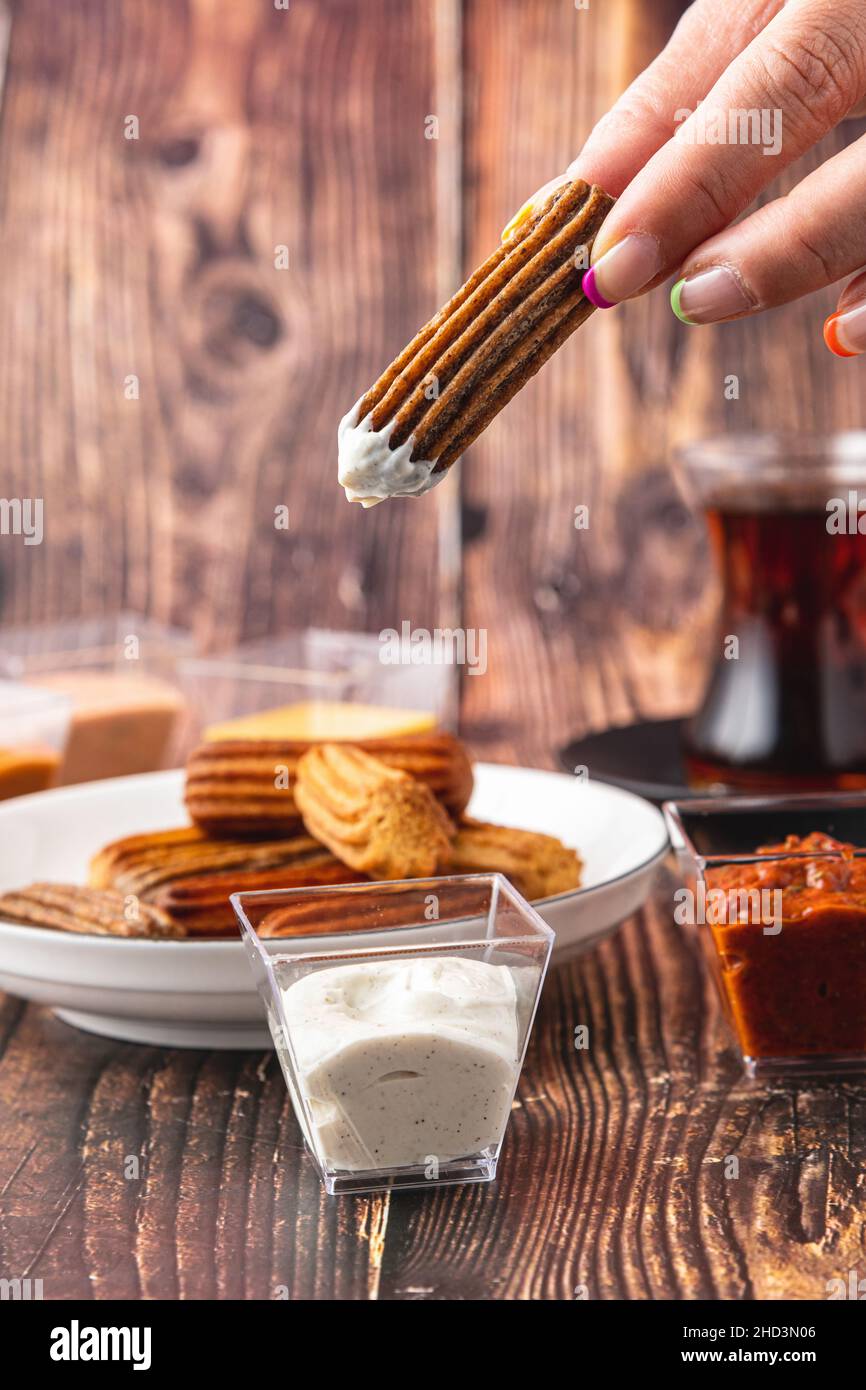 Churros con curry, olive e concentrato di pomodoro su tavola di legno con tè turco Foto Stock