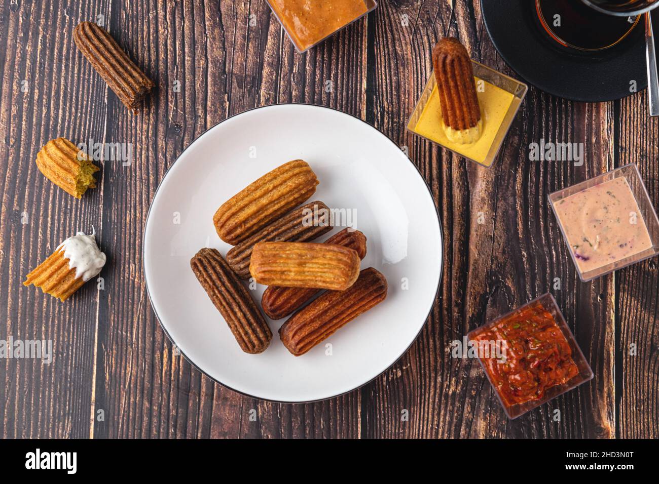 Churros con curry, olive e concentrato di pomodoro su tavola di legno con tè turco Foto Stock