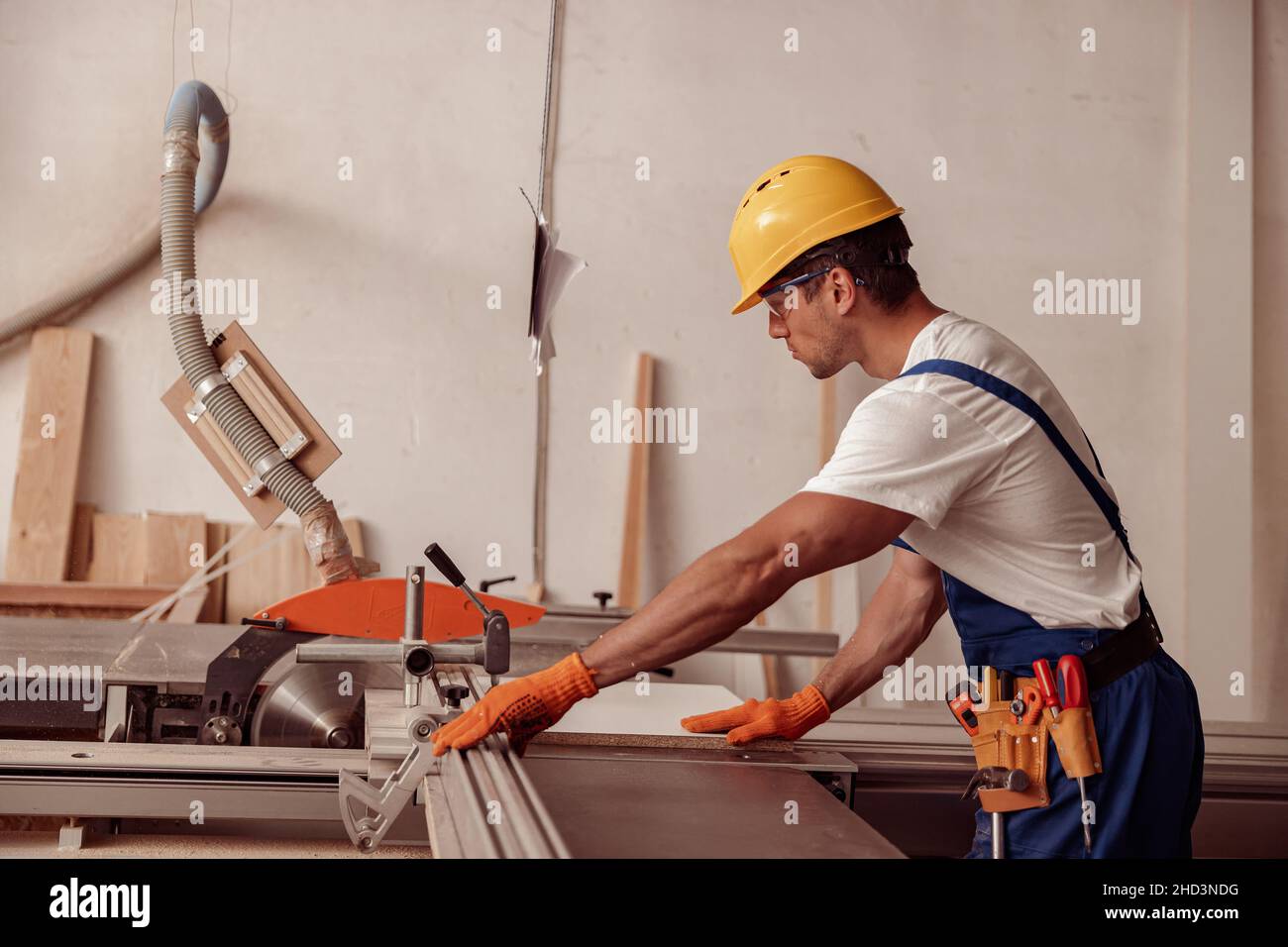 Costruttore maschile che utilizza la macchina per la lavorazione del legno in officina Foto Stock