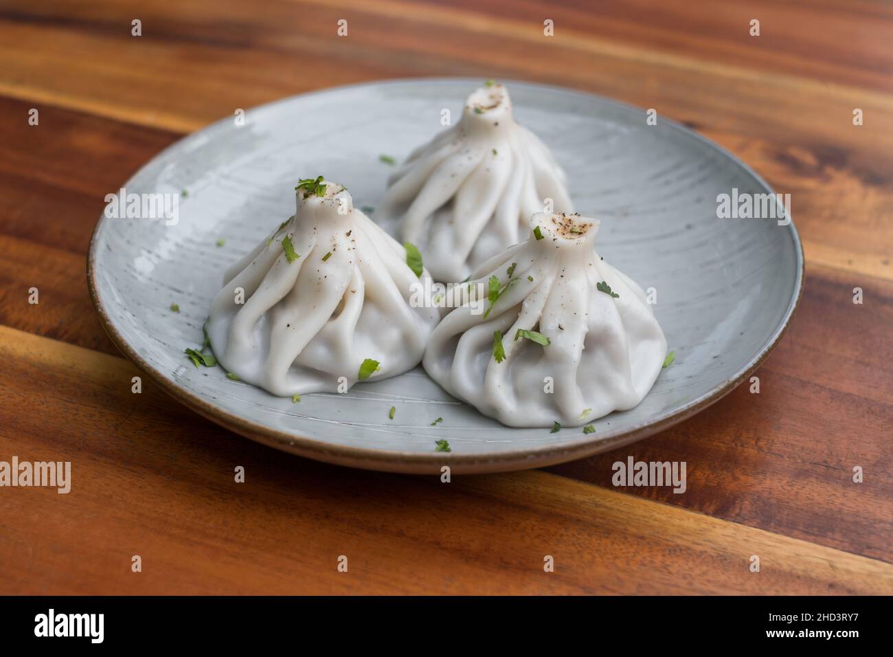 Cucina nazionale georgiana. Khinkali con carne. Khinkali su un piatto su sfondo di legno. Vista dall'alto, da vicino con spazio di copia. Foto di alta qualità Foto Stock