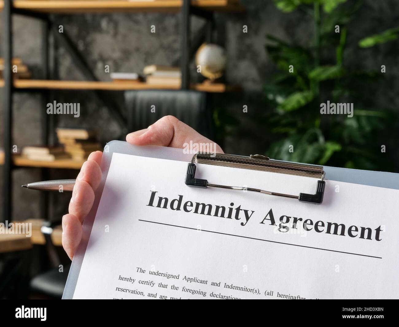 Mano tiene il contratto di indennità per la firma nell'ufficio. Foto Stock