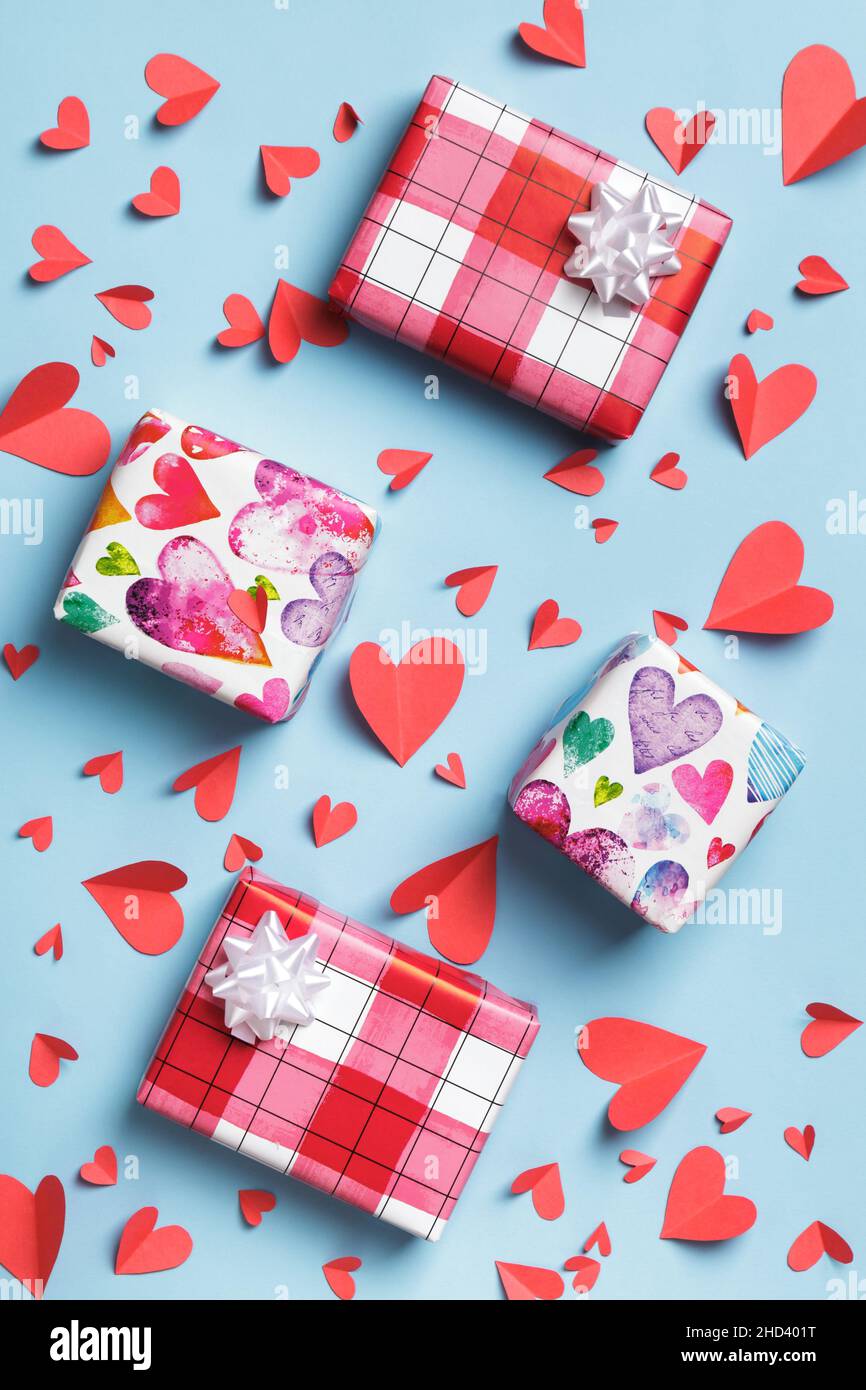 Cuori e scatole di carta rossa con regali su sfondo blu. Biglietti di auguri per il giorno della mamma San Valentino. Vista dall'alto, disposizione piatta Foto Stock